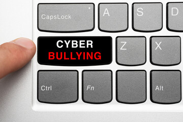 finger reaches out to press a black key with the word cyber bullying on a computer keyboard. Cyberbullying concept.