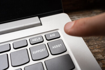 a finger reaches out the Help, aid, support, assist buttons in the corner of the computer keyboard. help and support in difficult life situations