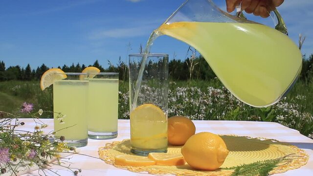 Pouring fresh squeezed lemonade into cool drinking glass at a Summer picnic in the countryside