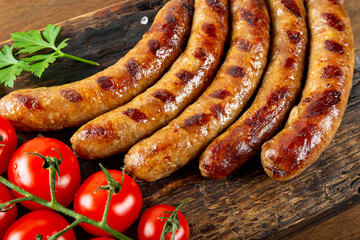  Grilled minced beef and pork sausages with barbecue sauce on wooden board close up