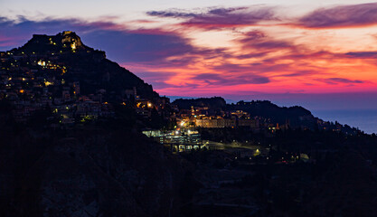 Colorful sunrise lights up the sky over Taormina, Sicily