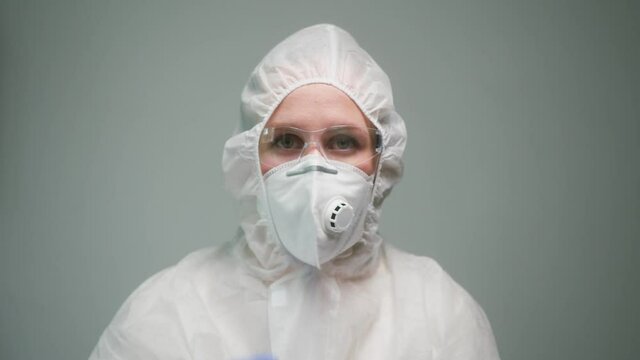 Close-up of overworked doctor or researcher dressed in protective suit ppe mask in laboratory in hospital, female nurse wearing medical uniform, portrait of tired woman chemist in plastic glasses. 