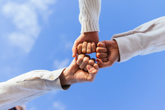 Crop people stacking hands under blue sky