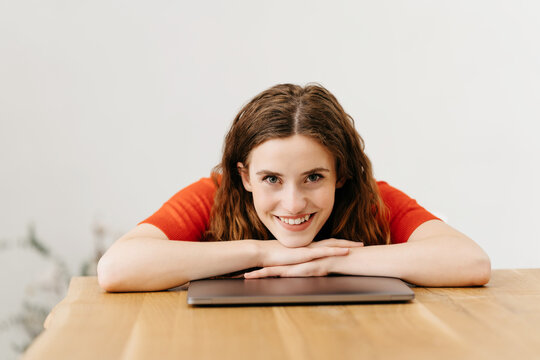 Relaxed young woman leaning on a laptop smiling at camera