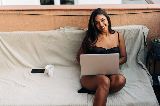 Young Hispanic female using netbook on balcony