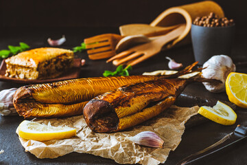 Mackerel. Smoked mackerel with additions. Fish with spices. Smoked food on a dark background. - obrazy, fototapety, plakaty