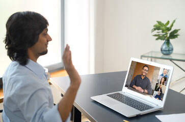 Indian man using computer application for distance video communication with coworkers, greeting webinar participants, meeting online, looking at the laptop screen with diverse people profiles