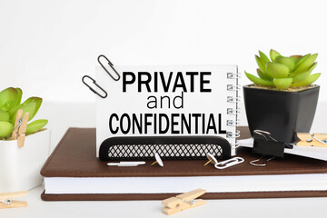 PRIVATE and CONFIDENTIAL. business card holder on a work table, on a notebook, near a flowerpot