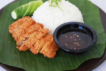 Rice with fired chicken and chili sauce put on the banana leaf serve in the Thai Restaurant