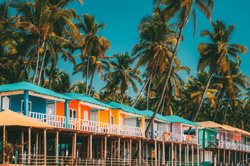 Canacona, Goa, India. Famous Painted Guest Houses On п Beach Against Background Of Tall Palm Trees...
