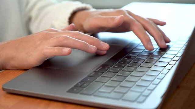 Women's beautiful hands typing on a laptop keyboard close-up. Blurred background.
