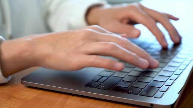 Women's beautiful hands typing on a laptop keyboard close-up. Blurred background.