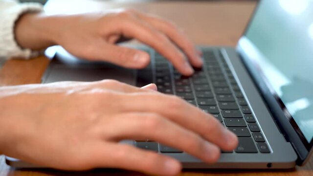 Women's beautiful hands typing on a laptop keyboard close-up. Blurred background.