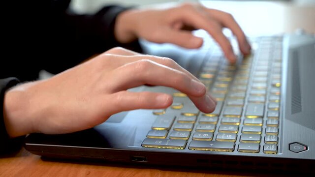 Women's beautiful hands typing on a laptop keyboard close-up. Blurred background.