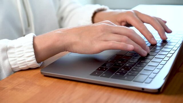 Women's beautiful hands typing on a laptop keyboard close-up. Blurred background.