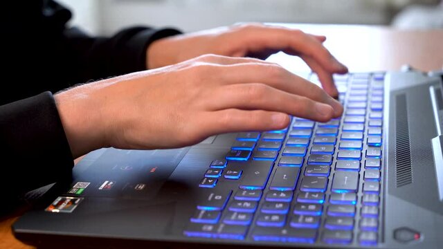 Women's beautiful hands typing on a laptop keyboard close-up. Blurred background.