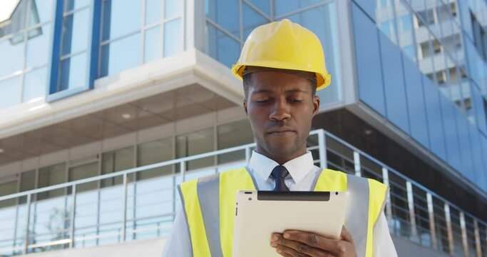 Business architect man wearing hardhat and west standing outdoors of building using digital tablet