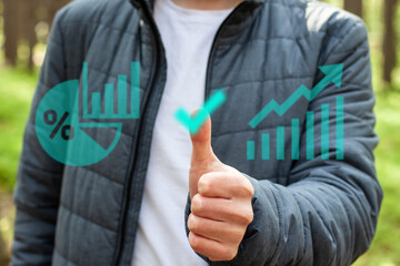 A young man clicks on a digital hologram at a remote work. The concept of business work outside the city. The man monitors the statistics of sales and income growth