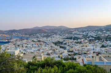 Fototapeta na wymiar Panoramic View of Ermoupolis City, Syros Island, Greece from Above at Sunset. Beautiful Bay and View of the Aegean Sea, Mountains and Sky. Traditional White Houses, Villas and Port. 