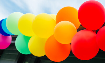 Garland of multicolored rainbow balloons against blue sky