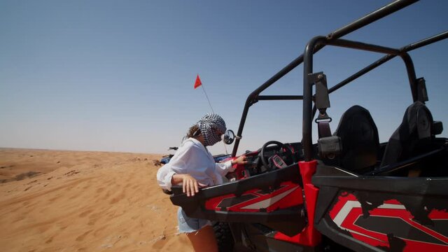 Young woman entering a sand buggy on a desert tour. Woman preparing to drive an offroad vehicle in the desert