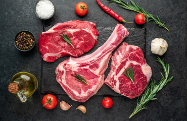 Assorted raw beef steaks. Tomahawk steak and ribeye steaks on stone background
