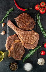 Variety of grilled beef steaks. Grilled tomahawk steak and ribeye steaks on stone background