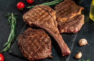 Variety of grilled beef steaks. Grilled tomahawk steak and ribeye steaks on stone background