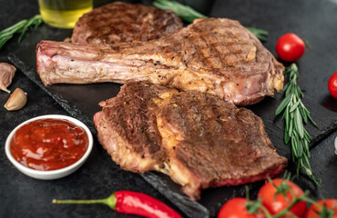 Variety of grilled beef steaks. Grilled tomahawk steak and ribeye steaks on stone background