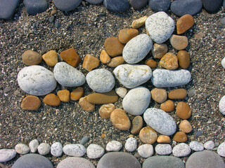 Beautiful background with a sunny composition of multi-colored stones in the form of a pattern on the seashore.