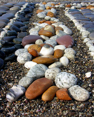 Beautiful background with a sunny composition of multi-colored stones in the form of a pattern on the seashore.