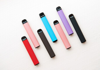 Layout of colorful disposable electronic cigarettes on a light texture background. The concept of...