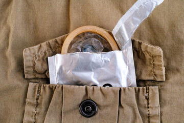Open condom package in pocket of a beige jacket.