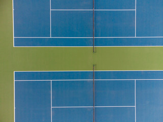 In the photo we see a tennis court. Yellow and blue colors. Sharp geometric lines. Minimalism. There are no people in the photo. There is a place for your insert. View from above.