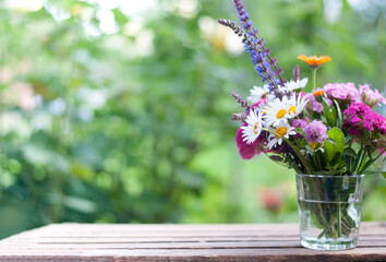 bouquet flowers in the glass vase on the nature blurred background with bokeh lights	