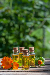 essential oil bottles with fresh calendula on the nature blurred background with copy space