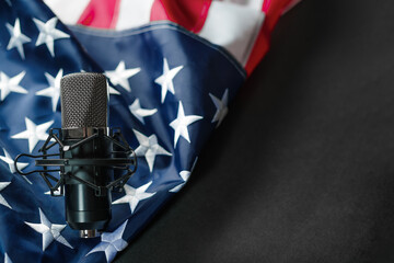 In the left corner of the photo we see the American state flag and microphone. Dark gray...