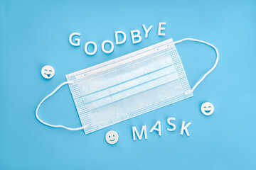 Goodbye mask phrase and face mask isolated on blue background. Concept of no longer be required to...