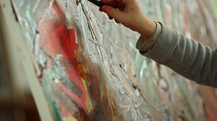 Unrecognizable painter hand making brush stroke on canvas in art studio.
