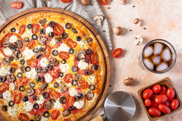 Pizza. Light background. In the right corner of the photo we see a pizza knife, tomatoes,...