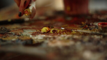 Unknown woman squeezing paint on palette on workshop. Contemporary art concept.