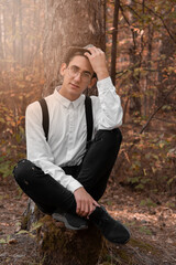 A young handsome guy in a shirt walks through the woods. Camping.