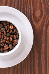 white cup, saucer and coffee beans on a wooden background