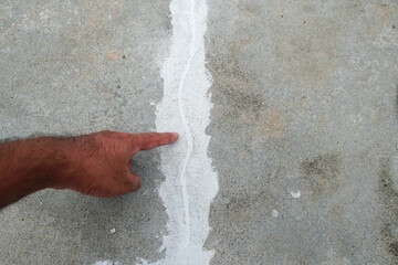Man hand finger pointing to cracked floor. Building problem and solution concept. Close up.