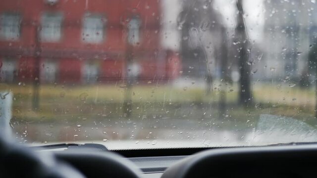 The rain is dripping on the car window. windshield wipers move along the windshield and remove water. View from the inside of the car.