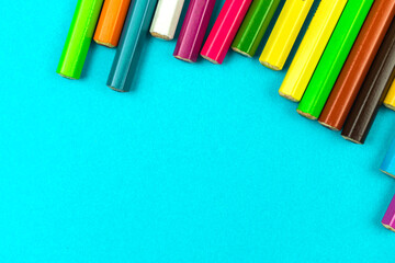 Different colour pencils lying on a bright desktop table top view photo, school stationery background concept