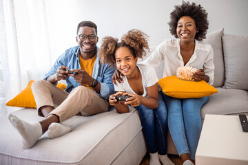 Smiling family sitting on the couch together playing video games. Playful family playing video...