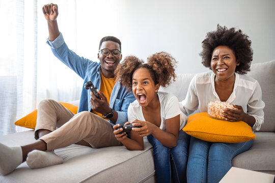 Closeup top view of a young african american family with children spending time at home during coronavirus pandemic in 2020. They are playing some video games in the living room.