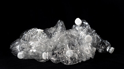 Plastic bottles, empty, piled up, ready for recycling, on black background