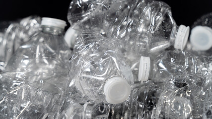 Plastic bottles, empty, piled up, ready for recycling, on black background